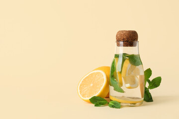 Wall Mural - Jar of water with lemons and mint leaves on light yellow background