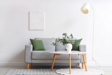 Wall Mural - Cozy sofa, coffee table with eucalyptus branches in vase and lamp near white wall in room