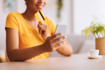 Poster - Online Payment Concept. Unrecognizable black lady holding credit card and cell phone, selective focus