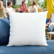 © trustmastertx - White square pillow on blue couch outdoors with blurred background of people socializing.