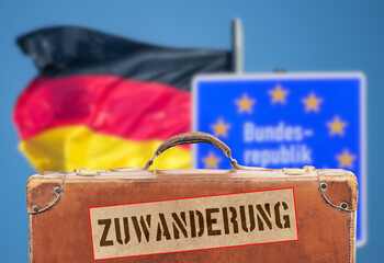 Grenze zu Deutschland und ein Reisekoffer mit dem Sticker Zuwanderung