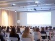 © jannoon028 - Attentive Audience Engaged at a Seminar Presentation with Large Screen Display in Conference Room