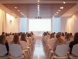 © jannoon028 - Audience Watching Presentation on Screen in Auditorium with White Chairs and Modern Lighting