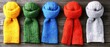 © Manatchaya - Five colorful knitted scarves arranged on a wooden surface, showcasing vibrant hues of yellow, green, blue, orange, and gray.