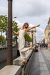 © Cavan - Joyful woman balancing playfully, Paris street, Arc de Triomphe