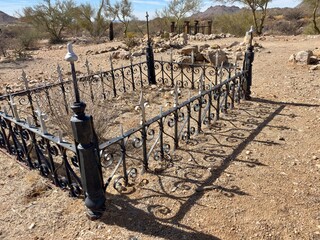 Wrought iron fence enclosing a grave in a desert pioneer cemetery.