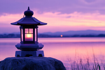 Wall Mural - Serene Japanese lantern at sunset by a tranquil lake, casting a warm glow with mountains in the background, enveloped in hues of purple and pink.