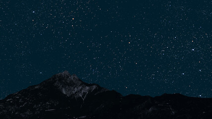 Wall Mural - a movement of stars in the night sky with the view of mountains..