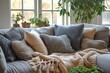 © Sunshine - Grey couch is covered in pillows and blanket, with potted plant in the background. Cozy and comfortable, relax and unwind
