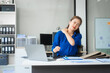© Phushutter - Asian businesswoman sits at her ergonomic desk, working on a laptop and mobile phone. Her posture ensures minimal strain, addressing neck pain, back pain, and preventing repetitive strain injuries.