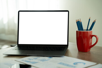 Wall Mural - A businessman is using a modern laptop on a white desk in a bright office, typing on a keyboard while viewing a blank screen, showcasing technology and communication.