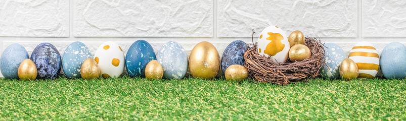 Wall Mural - easter eggs in a nest on green grass park or garden background. long banner format. copy space. east