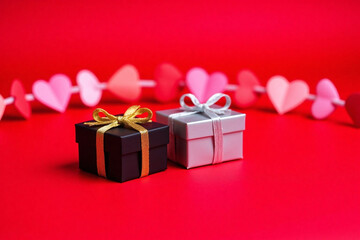 two gift boxes on red background with gold ribbon heart shaped garland