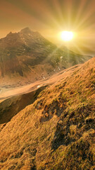Wall Mural - sunset landscape of a between two mountains with yellow grass on foreground