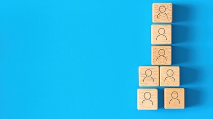 Poster - Wooden blocks with human icons arranged in a pyramid on a vibrant blue background, symbolizing teamwork and community.
