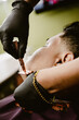 © Cristophercruzfoto - Un barbero con guantes negros afeita el cuello de un cliente con una navaja dorada. El cliente está relajado mientras recibe un servicio de precisión en una barbería moderna y profesional.