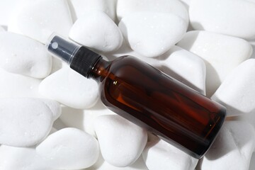 Wall Mural - Spray bottle of cosmetic product on white pebble stones, top view