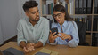 © Krakenimages.com - Business partners man and woman in office discussing smartphone displaying laptop and files on desk