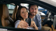 © Yuliia - Caucasian couple man woman girl guy female male family hugging cuddling happy smiling looking at camera celebrate buying own vehicle transport holding key in new car buying auto inside automobile