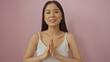 © Krakenimages.com - Young, asian, woman standing with hands together, smiling in front of an isolated, pink wall background.