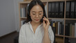 © Krakenimages.com - Woman wearing headset in office setting with bookshelves in the background