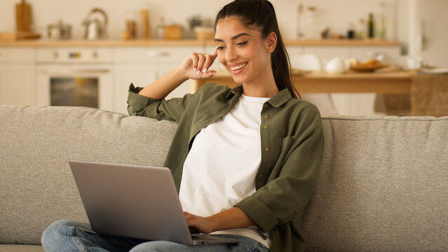 User freelance worker at home couch student receive good exams result online woman Indian girl Arabian female win laptop using browsing computer victory luck happy celebrate virtual game winning net