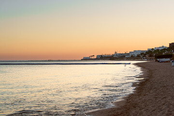 Wall Mural - tranquil beach at sunset reflecting warm colors over calm waters near coastal town