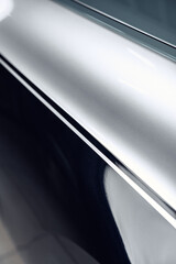 Poster - Close-up view of shiny metallic surface reflecting light in a modern indoor space