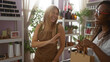 © Krakenimages.com - Women interacting and smiling in a vibrant home decor store filled with plants, shelves, and various decorative items, highlighting a friendly customer service environment