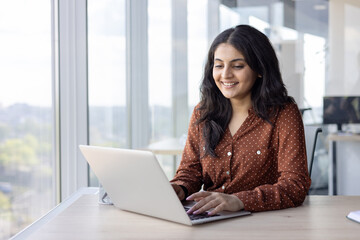young successful woman working inside office with laptop. confident and happy businesswoman smiling 
