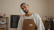 © Krakenimages.com - Handsome young arab man with a beard in a bakery shop, standing indoors wearing a brown apron in front of a chalkboard menu.