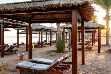Wall Mural - cozy beach cabanas line the shore at sunset in a tranquil seaside location