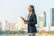 © StockPhotoRepublic - Young Asian Businesswoman Using Phone While Holding Coffee in Modern City Outdoors