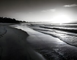 Black-and-white image of a deserted beach at dawn, with gentle waves and the interplay of light and shadow creating a peaceful, timeless scene