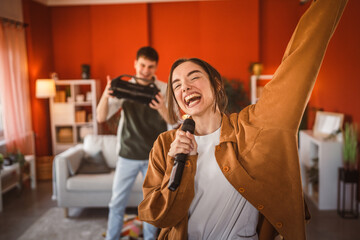 young woman hold microphone and sing karaoke have fun at home