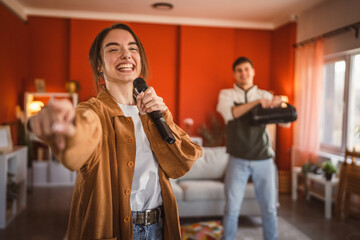 young woman hold microphone and sing karaoke have fun at home