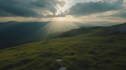 Canvas Print - Sun rays breaking through clouds over mountain meadow.