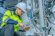 © reewungjunerr - Asian electric engineer holding clipboard for checking and monitoring the electrical system in the control room,Technician thailand people working