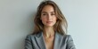 © Michael - Confident young woman in a gray blazer poses against a neutral background with a serious expression