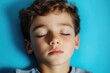 © Fotograf - A young boy sleeps with his eyes shut, showing relaxation and rest