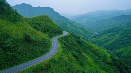 Poster - A scenic view of a winding road surrounded by lush green hills and valleys