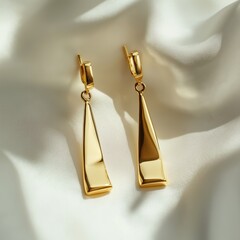 Wall Mural - Elegant gold dangle earrings on luxurious satin background