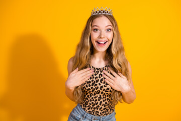 Wall Mural - Charming young woman in leopard print top smiling with surprise against a vibrant yellow background