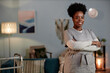 © Seventyfour - Medium full portrait of African American female social worker wearing grey uniform posing with arms crossed looking at camera with friendly smile during house visit to patient, copy space