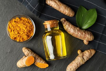 Wall Mural - Tumeric oil, powder and roots on black table, flat lay