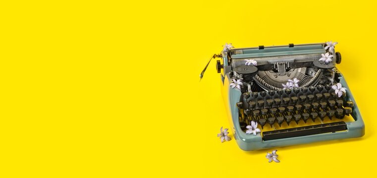 Vintage typewriter and flowers on yellow background with space for text
