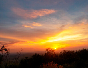 Fototapete - Atardecer sobre la montaña, con cielo naranja, amarillo y azul