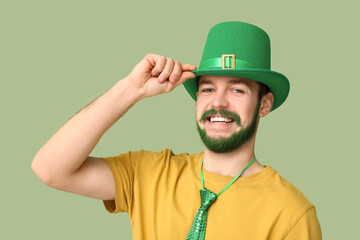 Young man in leprechaun hat with green beard on green background. St. Patrick's Day celebration