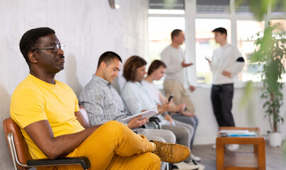 Wall Mural - Middle-aged male visitor waiting for his turn sitting on chair in hall of health center