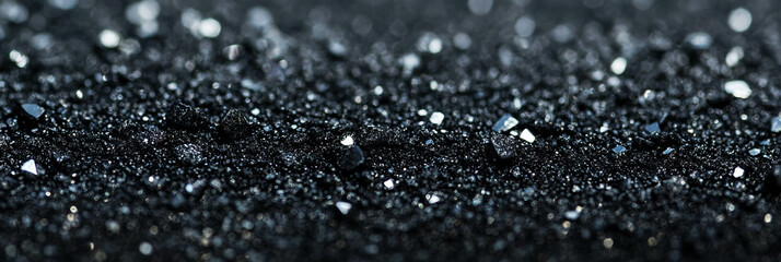 Poster - Wet black sand creates a reflective surface under shimmering light at the shoreline